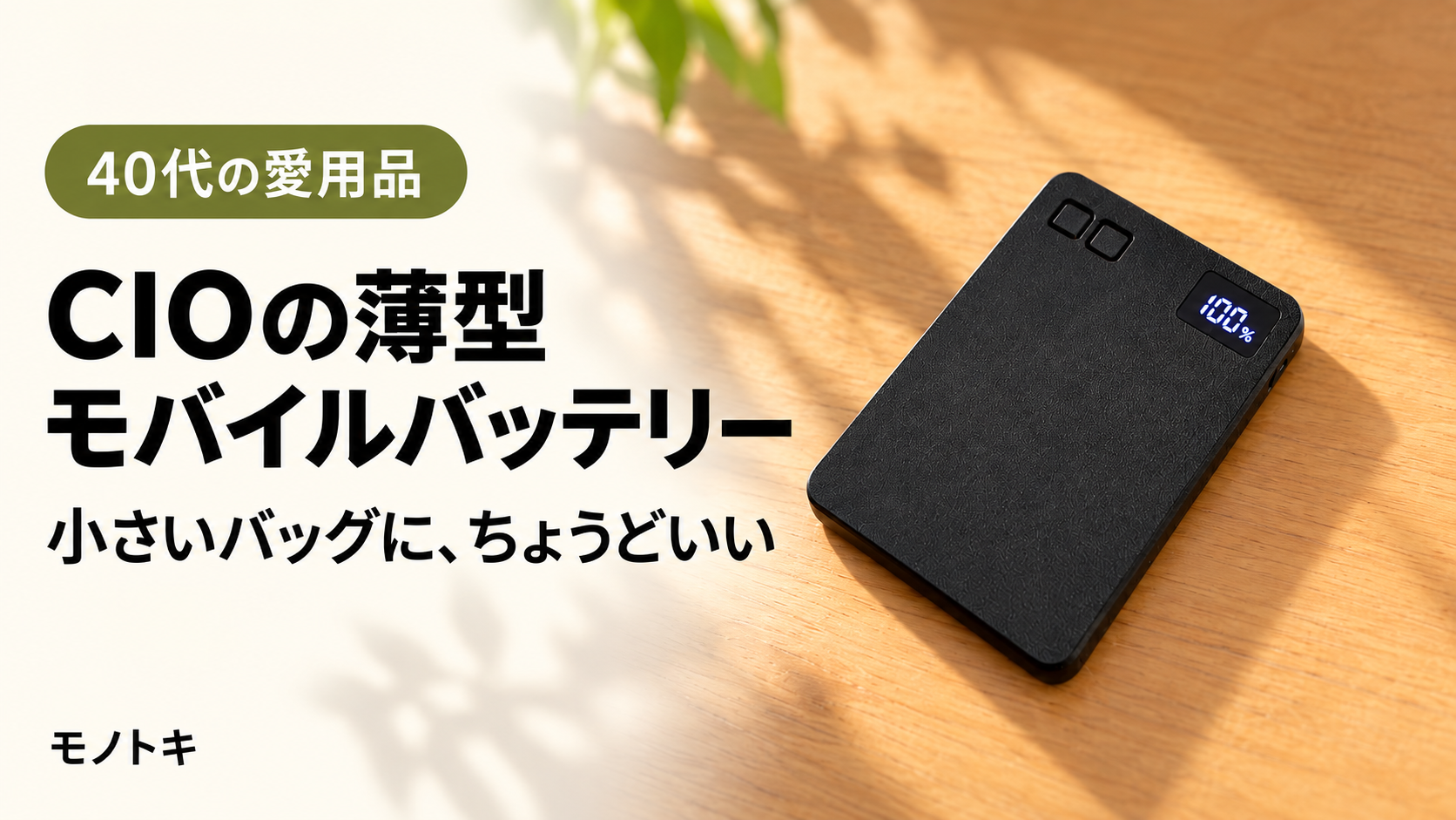 木のテーブルに置いた黒いCIO SMARTCOBY SLIMの実物写真をもとにした画像。残量表示は100％で、「CIOの薄型モバイルバッテリー 小さいバッグに、ちょうどいい」の文字入り