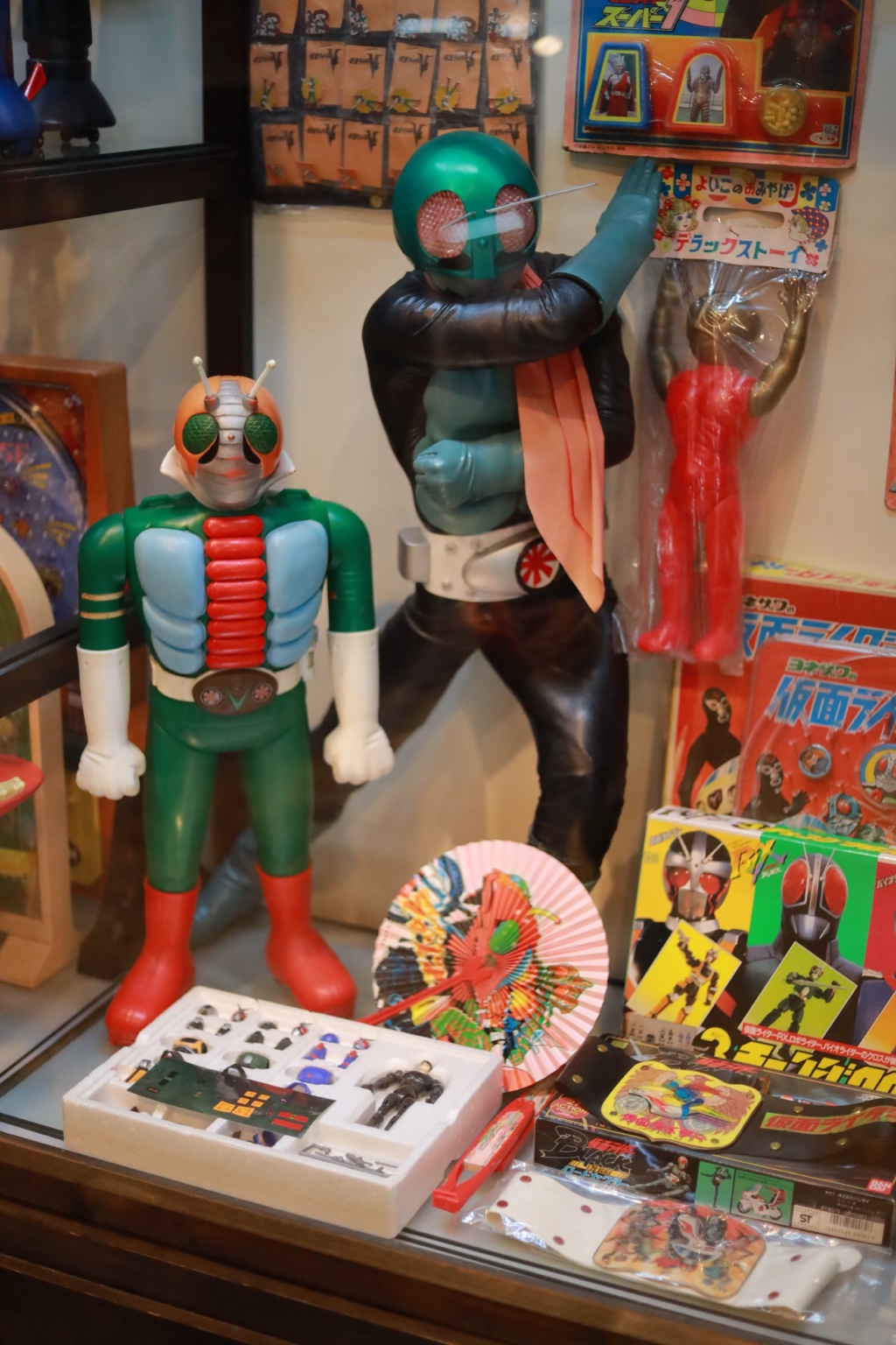 ケースの中に並ぶ、仮面ライダーの人形と昔のおもちゃ