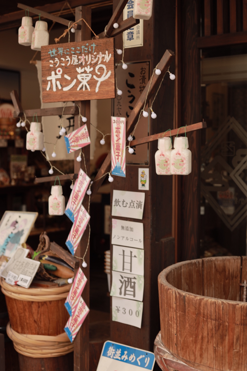 ポン菓子の木の看板や甘酒の札、木桶が並ぶレトロな店先